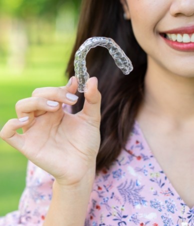 Woman holding a Clear Correct clear aligner outdoors
