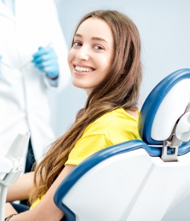 Smiling woman in yellow blouse sitting in dental chair