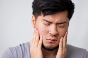 Frowning man dealing with pain of TMJ disorder