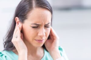 Grimacing woman struggling with tinnitus