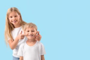 Two smiling children standing against blue background