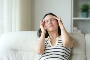 Woman sitting on sofa, suffering migraine attack