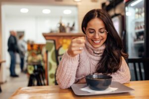 Woman eating tasty soup in a café